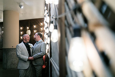 Grooms embracing each other in hotel courtyard