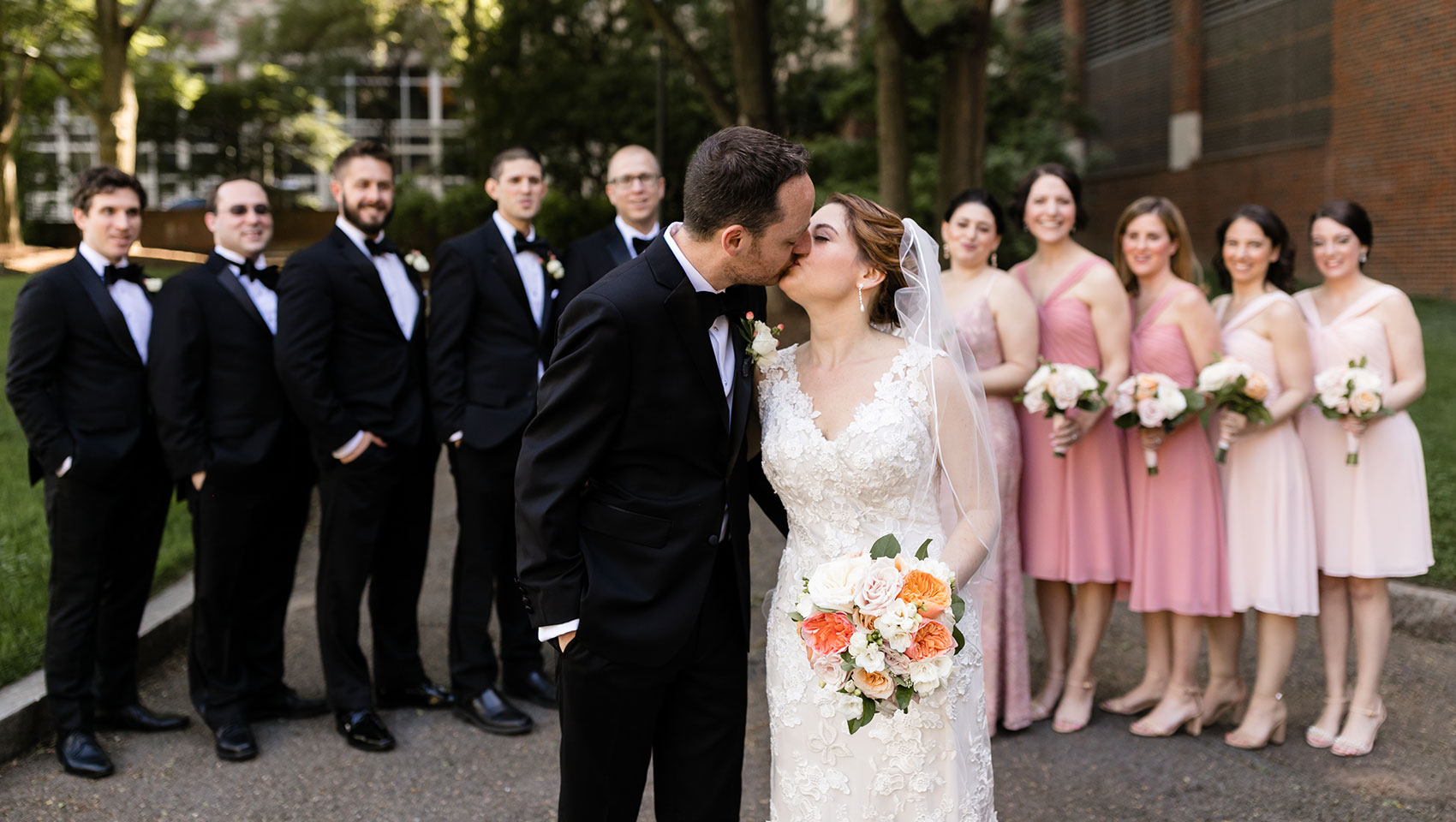 Bride and groom kissing in front of wedding party