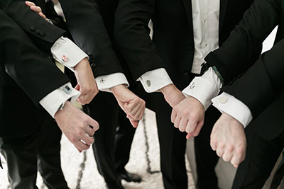 Groomsmen showing off different cufflinks