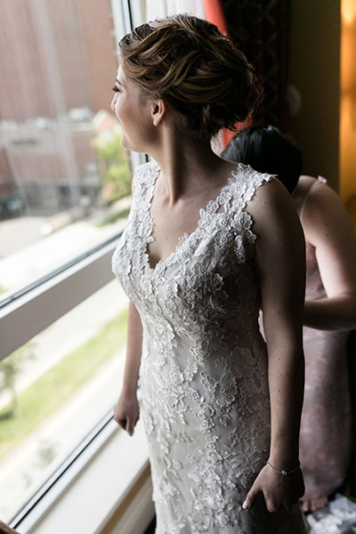 Bride looking out window in wedding dress