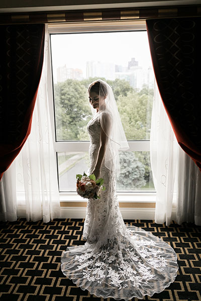 Bride by window in wedding dress