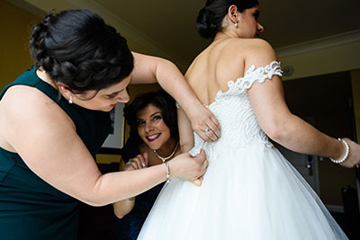 Bride having wedding dress back adjusted