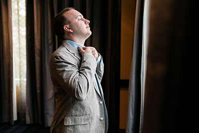 Groom fixing collar by window