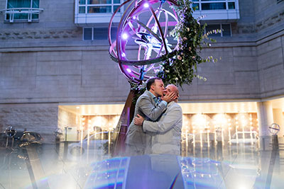 Grooms kissing in hotel courtyard