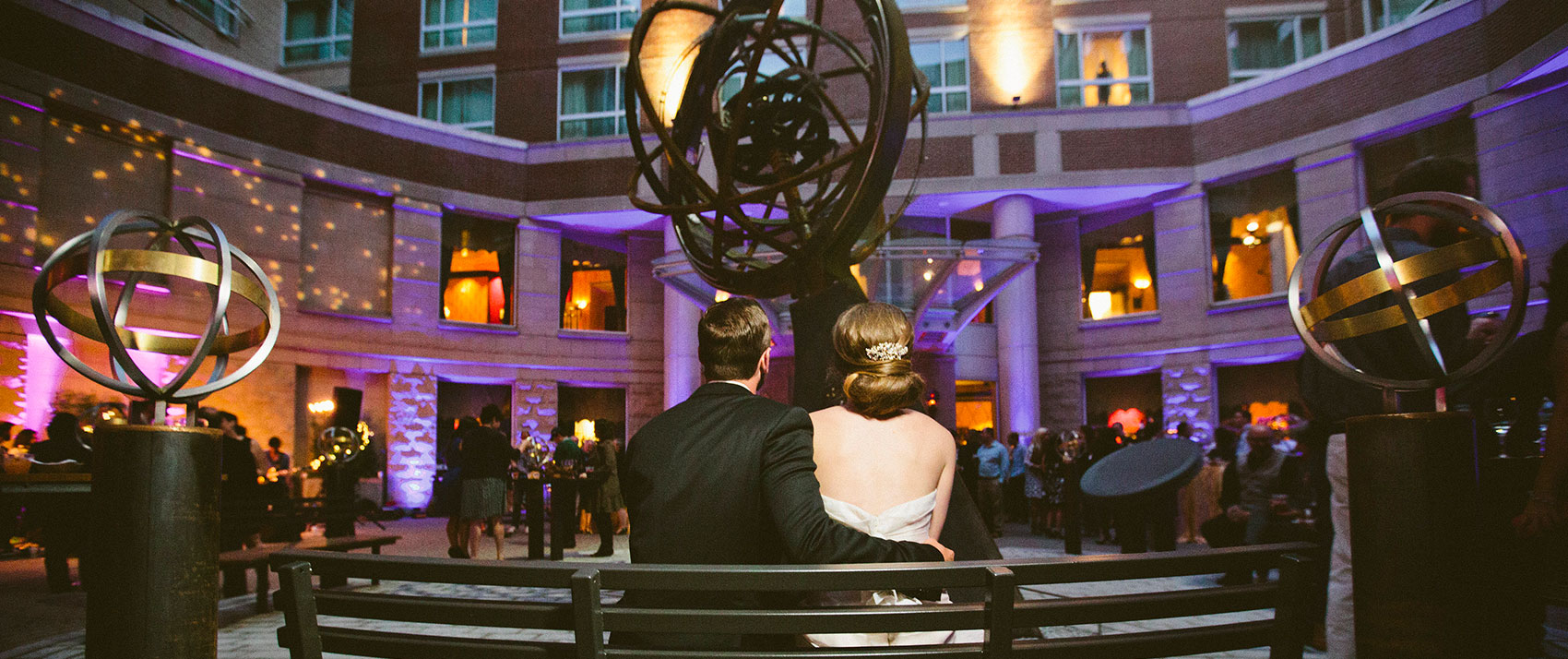 bride and groom sitting on bench in front of celeste